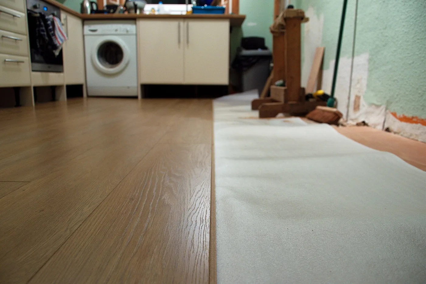 Houtlook plaklaminaat in een keuken met wasmachine en ondervloer in aanleg