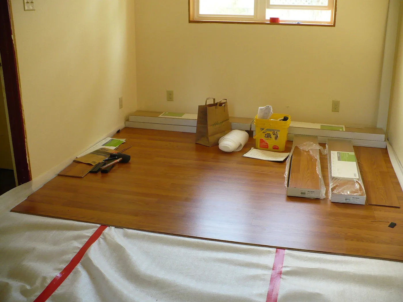 Een kamer met losse plaklaminaatplanken en ondervloer tijdens het werk